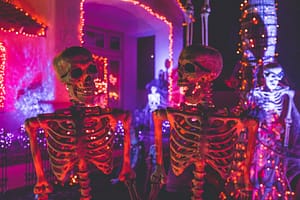 two skeleton near white concrete building with string lights at daytime